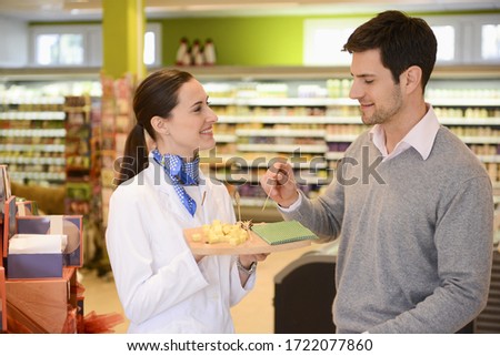 Sales assistant offering customer cheese in an organic grocery store