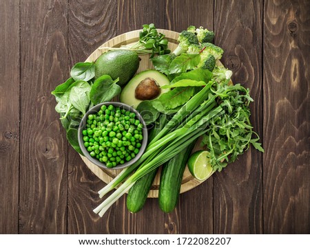 Top view of healthy organic food: green vegetables and herbs on dark wooden background. Source of protein for vegetarians. Royalty-Free Stock Photo #1722082207