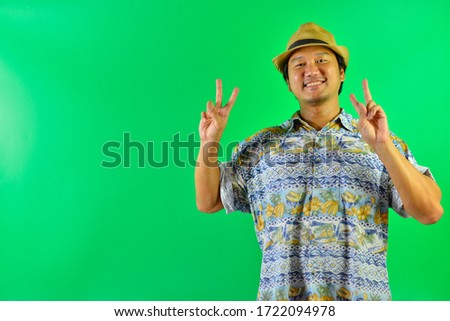 Asian tourists wearing straw hat and showing two finger or peace on over green screen background.