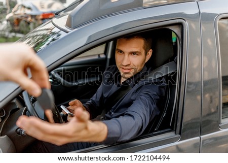 A young man in a shirt sits in a car. Diller gives him the keys to a new car. Auto sale, urban environment and traffic concept Royalty-Free Stock Photo #1722104494