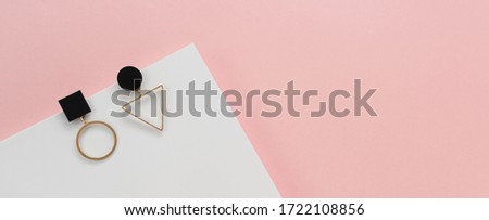 Top view of geometric design modern earrings pair on pink and white background with copy space 