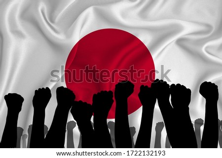 Silhouette of raised arms and clenched fists on the background of the flag of Japan. The concept of power, power, conflict. With place for your text. 