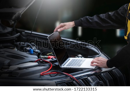 Mechanic using computer for diagnostics engine. Repairing car. Blur garage auto repair service in background. Royalty-Free Stock Photo #1722133315