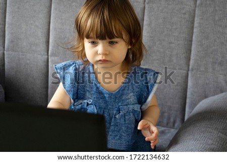 little cute girl intently watching cartoons on a laptop. Children and computer technology concept. Leisure during quarantine concept