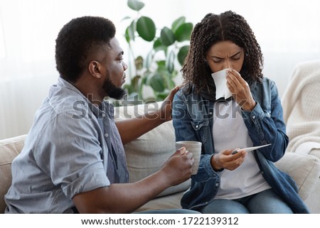 Care And Support. Loving Black Man Caring About His Ill Spouse Suffering From Coronavirus At Home, Offering Her Tea Royalty-Free Stock Photo #1722139312