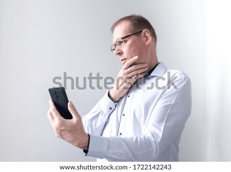 Focused thoughtful pensive businessman looking at phone screen isolated on white background