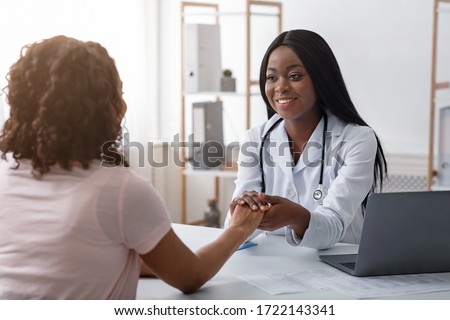 African cheerful female doctor holding patient hand, consultation at clinic Royalty-Free Stock Photo #1722143341