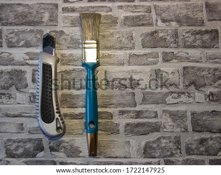 
Stationery knife with tassel and roulette on a brick background