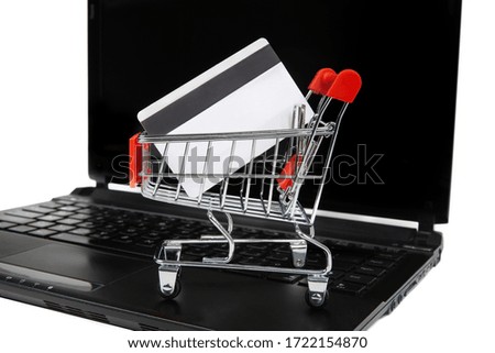 A credit card in a miniature shopping cart on a laptop. E-commerce and online shopping concept.