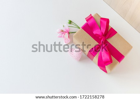 a flower, a crochet heart, a beautiful gift wrapped in a pink ribbon. White background. Copy space.