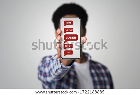 Cyberbullying concept. African American guy showing smartphone with abusive messages on screen, grey background. Collage Royalty-Free Stock Photo #1722168685