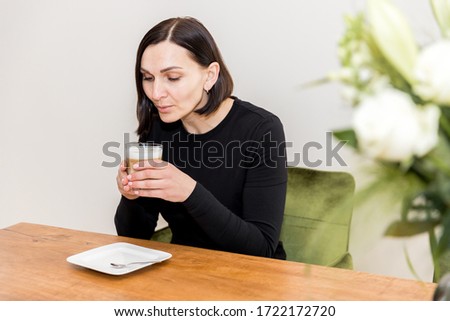 A caucasian woman sitting at a table drinking coffee 