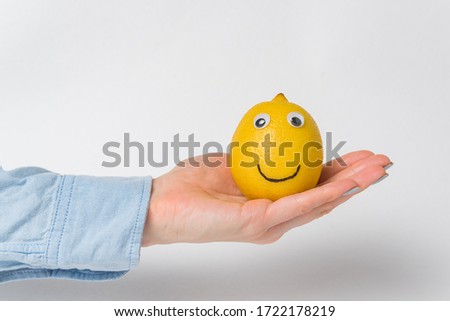 Funny lemon with Googly eyes lying on palm on white background.