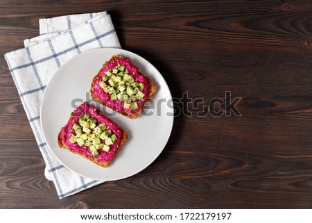 Variation of healthy rye toasts with avocado and beetroot on a plate. Delicious snacks, avocado sandwiches. Food composition, tasty vegan food. Copy space, top view.