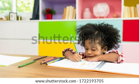 Young African American kid girl drawing with colored pencil, preschool child study at home school. Children education, self isolation, coronavirus outbreak social distancing or homeschooling concept Royalty-Free Stock Photo #1722193705