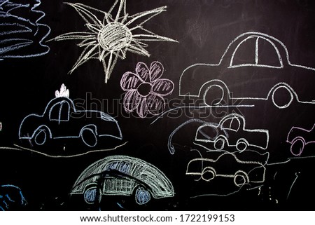 children's colorful drawings with chalk on a black slate blackboard. cars, flowers, the sun.