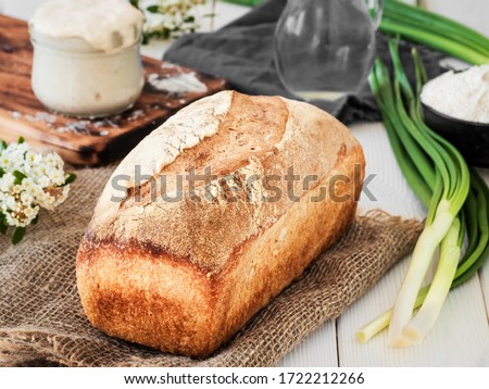 Freshly baked bread on burlap, sourdough and flour with a jug of water on a white wooden table. Hobbies, baking wheat bread at sourdough at home. Healthy food concept, traditional craft bread. Closeup