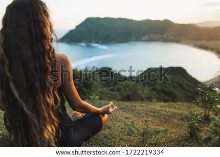Woman meditating yoga alone at sunrise mountains. View from behind. Travel Lifestyle spiritual relaxation concept. Harmony with nature. Royalty-Free Stock Photo #1722219334