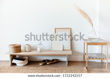 Wicker basket, glass vase, candle, photo frames on the table. A basket of books and wicker Slippers under the table.A branch of dried flowers in a glass vase on the right.