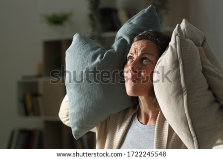 Annoyed adult woman suffering neighbour noise in the livingroom at night at home Royalty-Free Stock Photo #1722245548