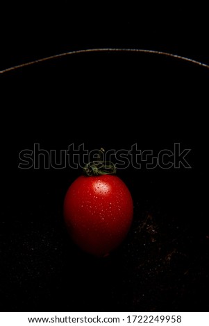Red fresh healthy tomato isolated on a black cuisine pan