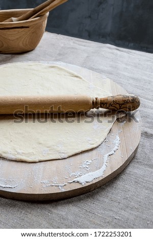 Wheat flour dough for making dumplings or pizza on a wooden Board with a rolling pin.