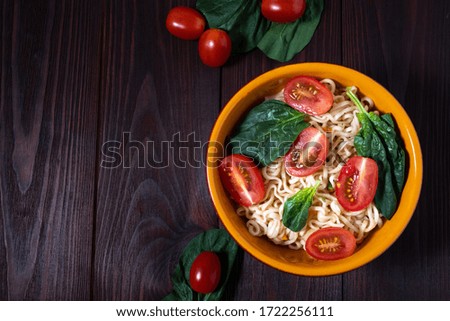 
Easy instant noodles.
Asian food. Noodles with broccoli, spinach, carrots and tomatoes on a wooden background. Instant noodles