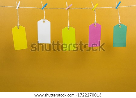Colored clothespins and labels are hung on a rope.
Multi-colored tags are hung on a scourge. Frame for text