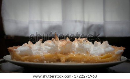 Lemon mirengue pie on a plate next to a window