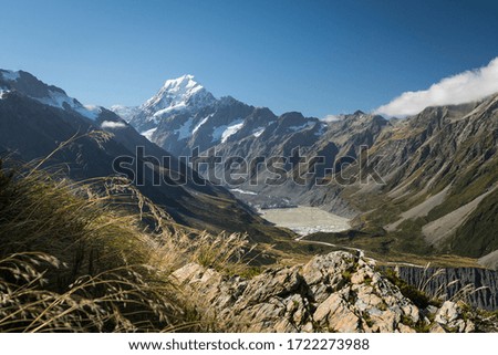Snow capped mountain with grass and rocks in foreground during the evening light. Mount Cook, New Zealand