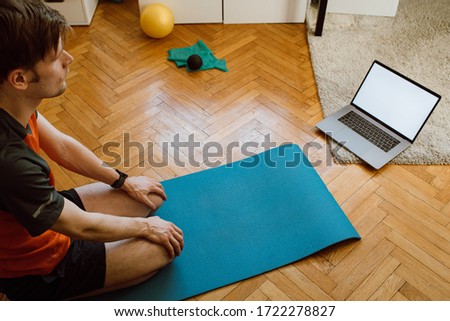 Self-care during stay at home COVID-19 Online yoga classes, Stretching exercises. Man at home with laptop. Attractive guy lying on fitness mat internet video online training blank laptop