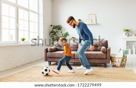 Full body bearded man in glasses trying to take ball from little boy in casual clothes while playing football near sofa at home together
 Royalty-Free Stock Photo #1722279499