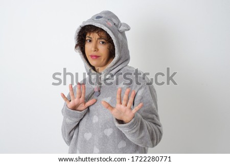 Beautiful brunette girl wearing pajama over isolated background afraid and terrified with fear, and disgusted expression stop gesture with both hands saying: Stay there. Panic concept