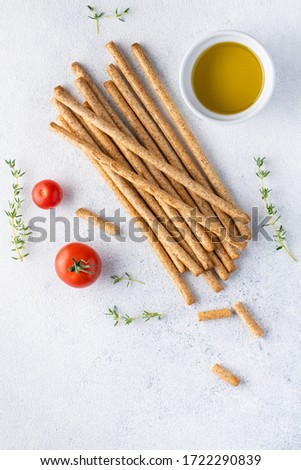 Organic Italian grissini or salted bread sticks and bread lying on a gray background. Fresh Italian snack for apero. Top view, copy space