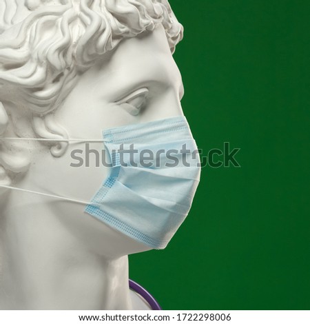 Medical protective mask on the face of the statue of Apollo.