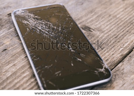 Smartphone display with broken glass on a wodden table