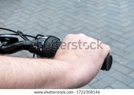 Close view of a hand on the right hand handle of a bicycle showing the gear changer