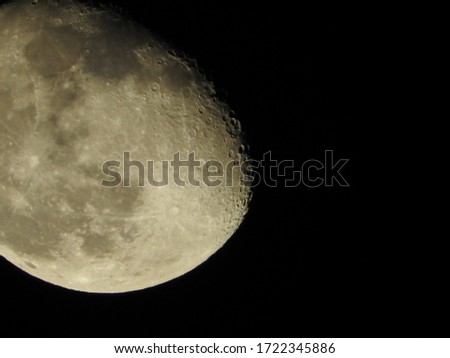 Moon in the foreground with a black sky, where you can see some details of the lunar surface. 