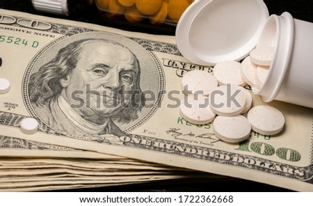 Stacked hundred Dollar bill with pills and medicine on top. Expensive health care in the United States.