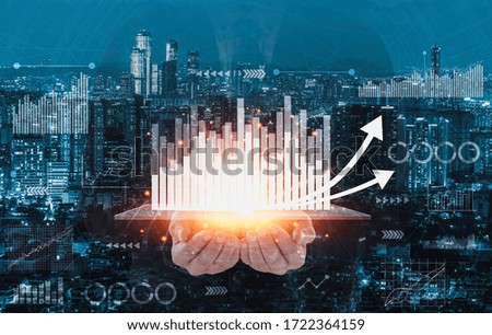 Businessman standing and holding visual sceeen with graph  icon and cityscape background.Business Construction Concept,Marketing concept