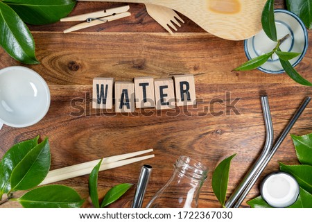 The wooden brick with words " WATER " on wooden background. ECO concept with recycling symbol and leaves.