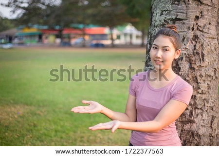 An Asian woman in a dark pink dress, in a gesture of consolation and having space in nature.