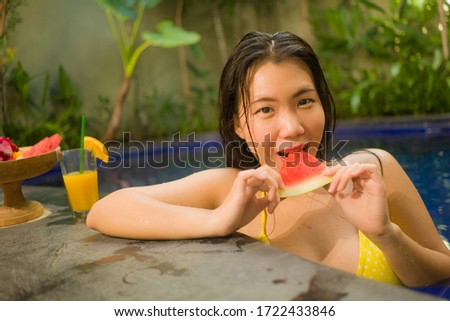 outdoors Summer lifestyle portrait of young beautiful and happy Asian Chinese woman in bikini enjoying vacation at swimming pool relaxed and cheerful at villa or luxury tropical resort
