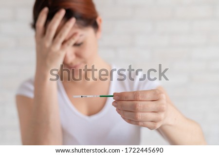 Frustrated woman shows a positive pregnancy test. Child free concept. Human chorionic gonadotropin. Two stripes. Unwanted child.