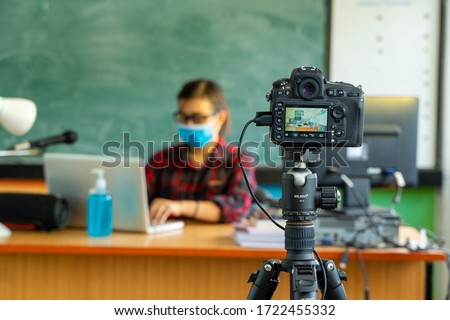 Teacher wearing protective mask to Protect Against Covid-19,Group of school kids with teacher sitting in classroom online and raising hands,Elementary school,Learning and people concept. Royalty-Free Stock Photo #1722455332