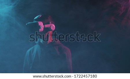 Portrait of a man in virtual reality helmet. Obscured dark face in VR goggles. Internet, darknet, gaming and cyber simulation.