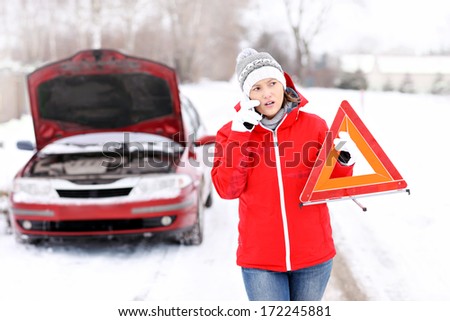 A picture of a young woman having a problem with a car on a winter road