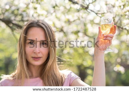 young woman in the park. In a hand a glass with champagne. Wine tasting. 
woman drinks from a glass