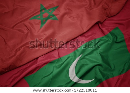 waving colorful flag of maldives and national flag of morocco. macro