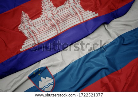 waving colorful flag of slovenia and national flag of cambodia. macro